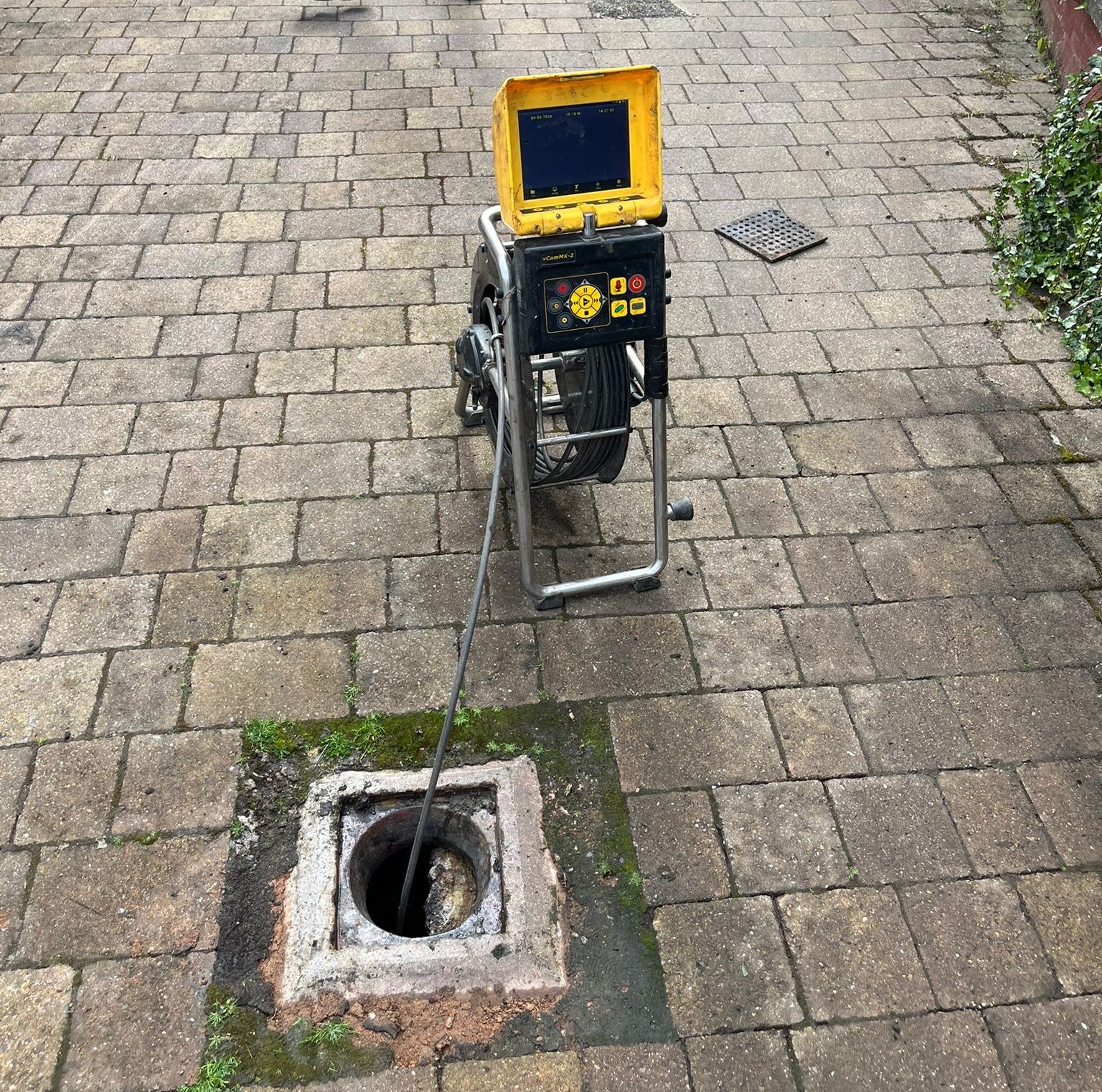 CCTV drain survey in Glasgow with camera reel over an open inspection chamber